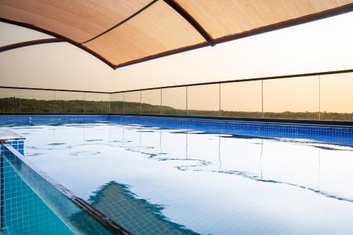 an indoor swimming pool with blue water and a wooden ceiling at Holitel Anjuna in Arpora