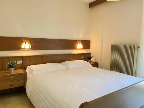 a bedroom with a large white bed with two lamps at Locanda La Ruscoletta in Telve