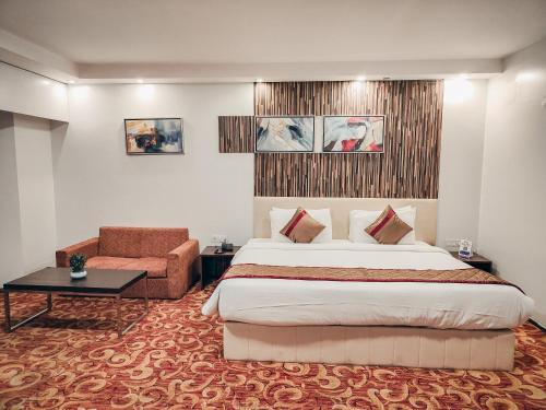 ein Hotelzimmer mit einem großen Bett und einem Stuhl in der Unterkunft The Altruist Hotel Kharadi in Pune