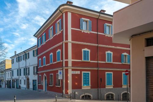a red building with blue windows on a street at LaMalatestina Suite - Apartment in front of the Castle in Rimini