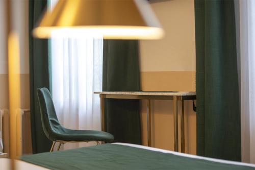 a room with a table and a chair and a lamp at Grand Hôtel Saint-Aignan in Saint-Aignan