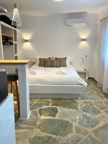 a bedroom with a white bed with a stone floor at Dryopis Studio in Kithnos