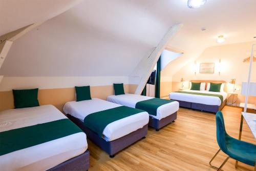 a room with three beds and a chair in it at Grand Hôtel Saint-Aignan in Saint-Aignan