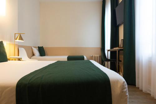 a hotel room with two beds and a television at Grand Hôtel Saint-Aignan in Saint-Aignan