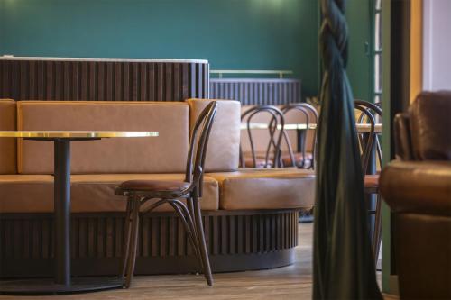 a bench with chairs and a table in a room at Grand Hôtel Saint-Aignan in Saint-Aignan