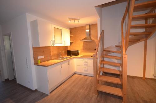 une cuisine avec des placards blancs et un escalier dans une pièce dans l'établissement Ferienwohnung Hagener Meer, à Mehrhoog