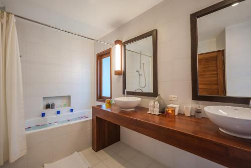 a bathroom with two sinks and a mirror and a tub at Vichuda Hills by RESAVA in Layan Beach