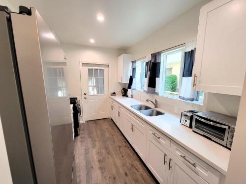 a white kitchen with a sink and a microwave at Perfectly located Pico Robertson ground floor 3 bedroom apartment Walk to restaurants WIFI TV Game Console Parking 5 minutes to Rodeo Drive in Los Angeles