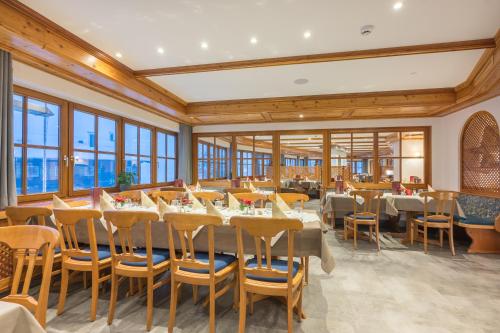 a dining room with tables and chairs and windows at IFA Alpenrose Hotel Kleinwalsertal in Mittelberg