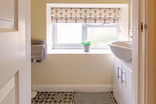 a bathroom with a sink and a window at Acorn Cottage in Quorndon