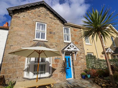 an umbrella in front of a house with a palm tree at The Haven in Marazion