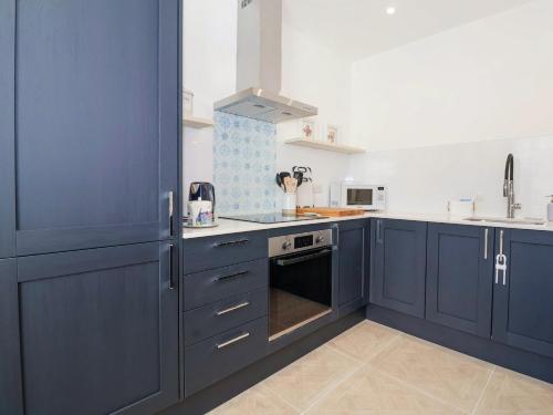 a kitchen with blue cabinets and a stove top oven at The Haven in Marazion