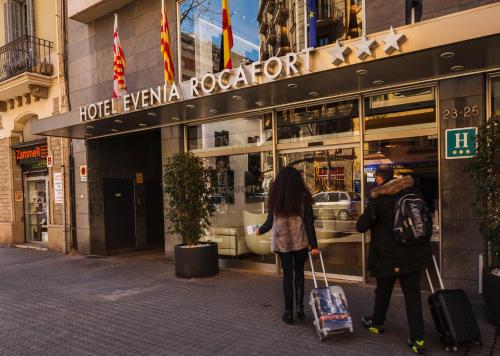a man and a woman walking in front of a store at Evenia Rocafort in Barcelona