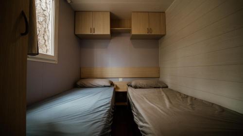 two beds in a small room with cabinets at Camping Cobijo in Vinuesa