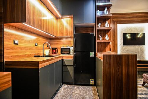 a kitchen with a black refrigerator and wooden cabinets at Luxury Poolside Retreat Elegant Apartment two rooms within a Seafront Hotel in Sharm El Sheikh