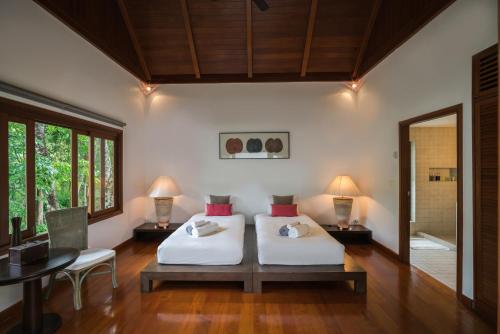 a bedroom with two beds and a table and a mirror at Vichuda Hills by RESAVA in Layan Beach