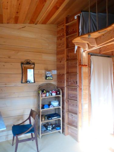 une pièce avec un mur en bois avec une chaise et une étagère dans l'établissement Studio de pleine nature idéal pour se ressourcer en solo, à Chenaillers-Mascheix