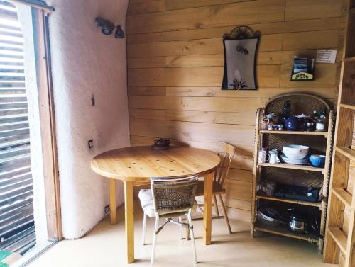 a table and chairs in a room with a wooden wall at Studio de pleine nature idéal pour se ressourcer en solo in Chenaillers-Mascheix