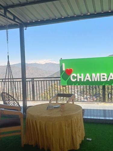 a table and a sign with a view of the mountains at Happy Homestay And Rooftop cafe in Chamba