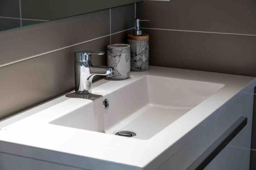 un lavandino in bagno con rubinetto e due tazze sopra di La cabane a Narbonne-Plage