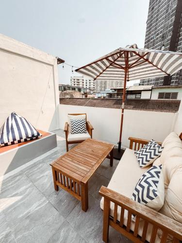 a rooftop patio with a table and chairs and an umbrella at Spacious Relaxing Townhouse with Rooftop in Ekamai in Bangkok