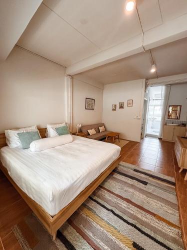 a bedroom with a large bed and a living room at Spacious Relaxing Townhouse with Rooftop in Ekamai in Bangkok
