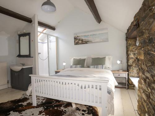 ein Schlafzimmer mit einem weißen Bett und einer Steinwand in der Unterkunft Riverwash Cottage in Penmaen-mawr