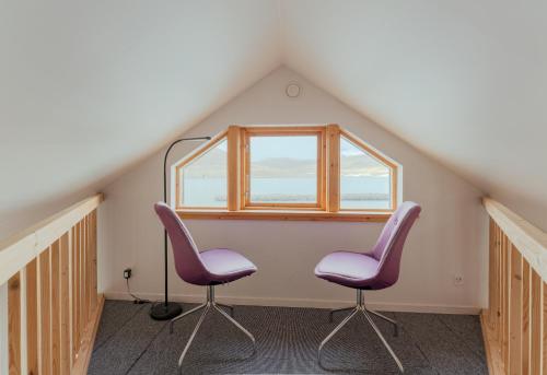 two chairs and a window in a attic at Neystastova - Boathouse Stay with Fjord Views in Hvalvík