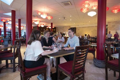 a group of people sitting at a table in a restaurant at Les Pagodes de Beauval in Saint-Aignan
