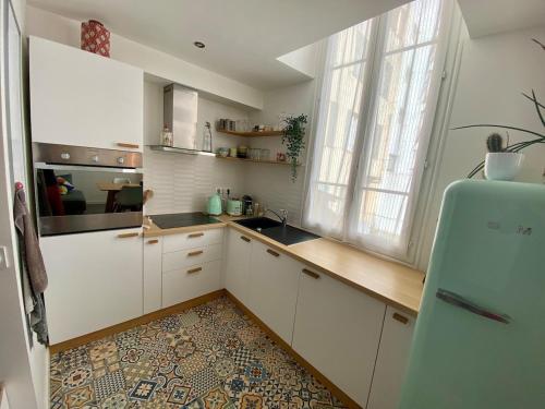 La cuisine est équipée de placards blancs et d'un réfrigérateur bleu. dans l'établissement Duplex 80m2 port de nice, direct aéroport avec le tram, à Nice