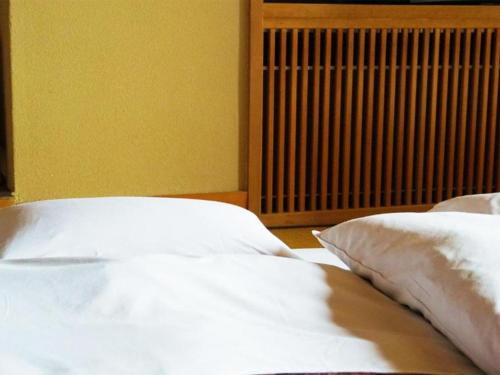 a bed with white sheets and pillows next to a radiator at Wakaki Ryokan - Nasu Yumoto Onsen in Nasu