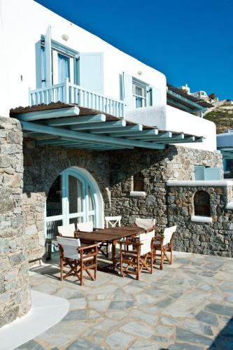a patio with a wooden table and chairs in front of a building at Sofia's Bungalows Mykonos in Mýkonos City