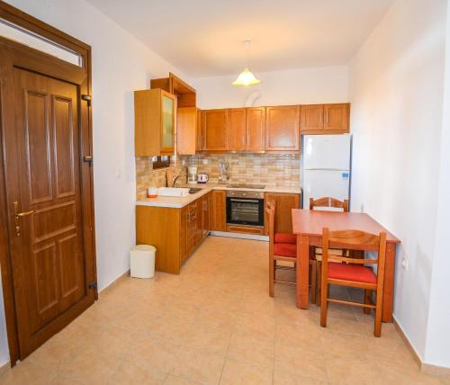 a kitchen with wooden cabinets and a table and a refrigerator at Petra Mare Babis in Akoumia
