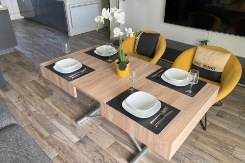 une table en bois avec des assiettes et des verres au-dessus dans l'établissement Appartement - Concarneau, à Concarneau