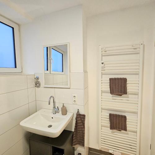 a white bathroom with a sink and a mirror at Urban Suites HBN in Heilbronn