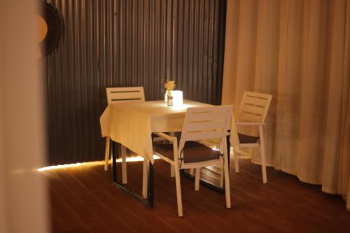 a table with four chairs and a white table with a vase at Kalih Villa in Kigali