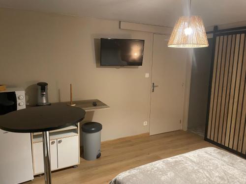 Cette petite chambre comprend une table, un lit et une télévision. dans l'établissement Chez Simon, à Ussel