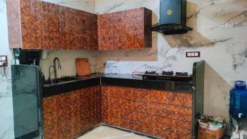 een keuken met houten kasten en een wastafel bij Sukdham Homestays Mathura! in Mathura