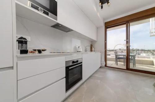 a kitchen with white appliances and a large window at Luxury Penthouse - Rooftop Pool - 100m to the Sea in Torrevieja