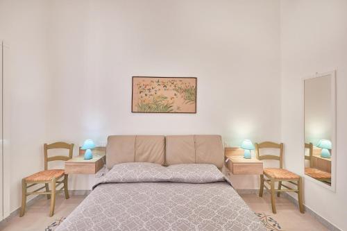 a bedroom with a bed and two chairs and a mirror at Zia Marì Casa Vacanze in Palermo