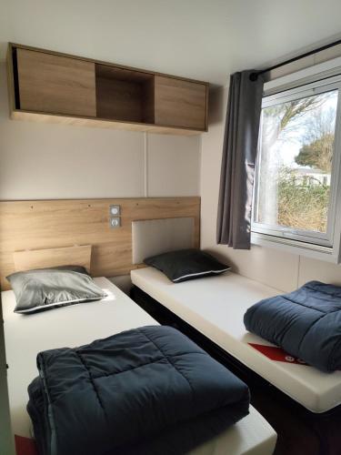 deux lits assis dans une pièce avec une fenêtre dans l'établissement KOKUA VACANCES Mobils Homes résidentiels camping 5 étoiles, à Saint-Georges-dʼOléron