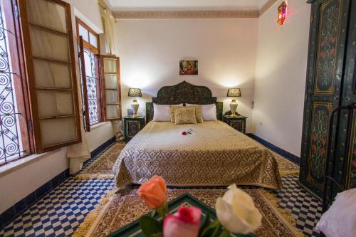 a bedroom with a bed and two windows at Riad Dar Bab Guissa in Fès