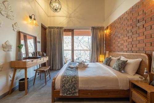 a bedroom with a bed and a desk and a brick wall at The Foresta Resort ,Mulshi in Paud