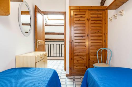 a bedroom with a blue bed and a wooden door at GuestHost Dreamy Stintino Seafront, AC and Parking in Stintino