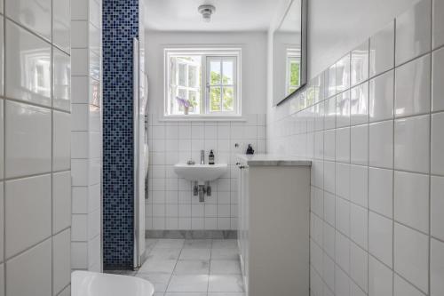 a white bathroom with a sink and a toilet at Villa Falsterbo in Skanör med Falsterbo