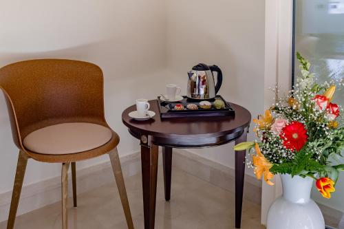 a table with a chair and a tea kettle and a vase with flowers at La Paloma Blanca Hotel in Sciacca