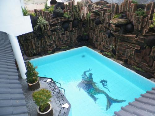 a swimming pool with a mermaid in the water at Bladok Hotel & Restaurant in Yogyakarta
