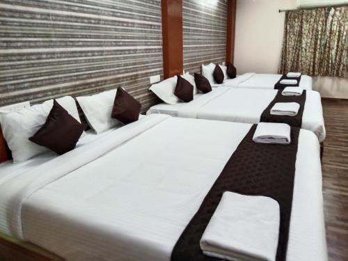a row of four beds in a room at Aurobay Resorts Pondicherry in Auroville