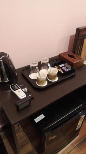 a tray with cups and glasses on a table at Chan Beach Resort & Hotel in Bahūr