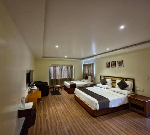 a hotel room with two beds and a desk at Hotel Glanton Manor in Ooty